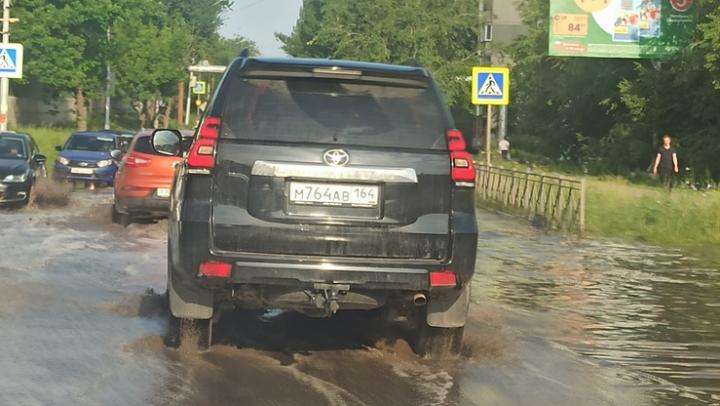 В Солнечном после дождя машины форсируют залитую водой дорогу